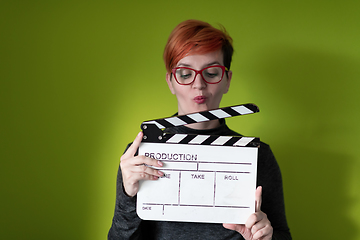 Image showing redhead woman holding movie  clapper on green background