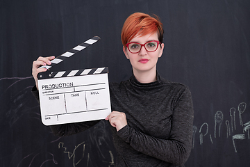 Image showing redhead woman holding clapper on black background