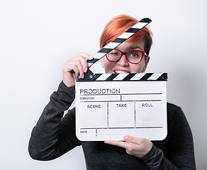 Image showing redhead woman holding movie  clapper on white background