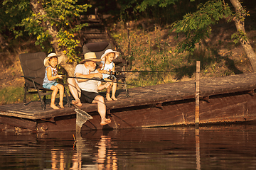 Image showing Cute little girls and their granddad are on fishing at the lake or river