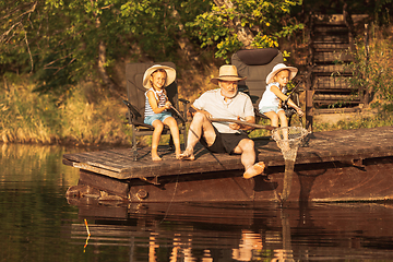 Image showing Cute little girls and their granddad are on fishing at the lake or river