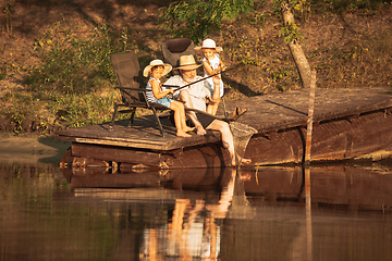 Image showing Cute little girls and their granddad are on fishing at the lake or river