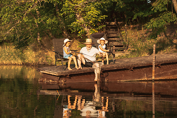 Image showing Cute little girls and their granddad are on fishing at the lake or river