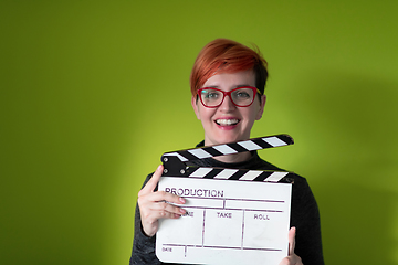 Image showing redhead woman holding movie  clapper on green background