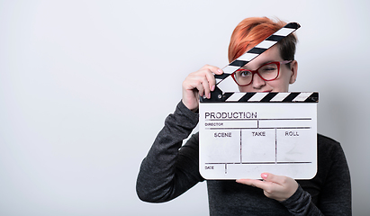 Image showing redhead woman holding movie  clapper on white background