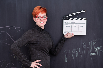 Image showing redhead woman holding clapper on black background