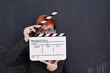 Image showing redhead woman holding clapper on black background