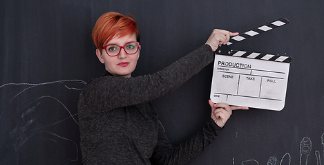 Image showing redhead woman holding clapper on black background