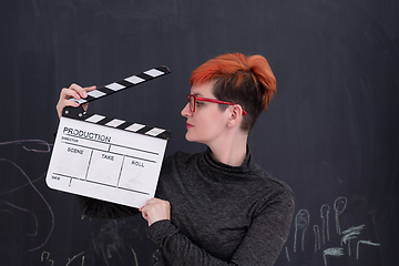 Image showing redhead woman holding clapper on black background