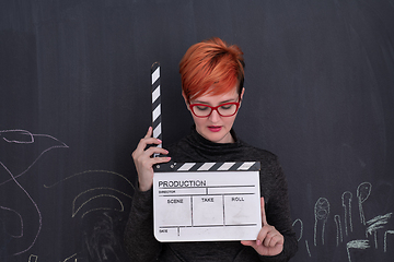 Image showing redhead woman holding clapper on black background