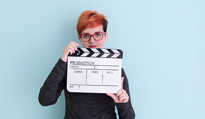 Image showing redhead woman holding movie  clapper on cyan background