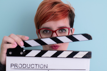 Image showing redhead woman holding movie  clapper on cyan background