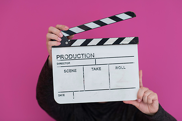 Image showing redhead woman holding movie  clapper on pink background