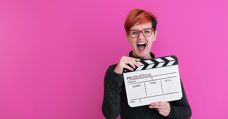 Image showing redhead woman holding movie  clapper on pink background