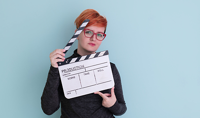 Image showing redhead woman holding movie  clapper on cyan background