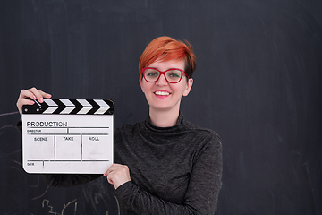 Image showing redhead woman holding clapper on black background