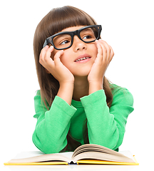 Image showing Young girl is daydreaming while reading book