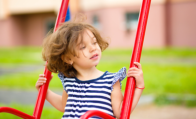 Image showing Young happy girl is swinging in playground