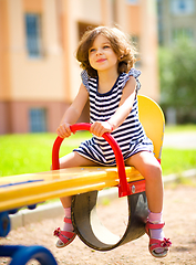 Image showing Young happy girl is swinging in playground