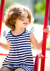 Image showing Young happy girl is swinging in playground