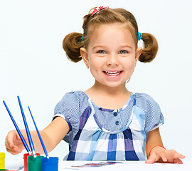 Image showing Little girl is painting with gouache