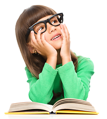 Image showing Young girl is daydreaming while reading book