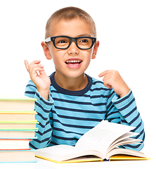 Image showing Young boy is daydreaming while reading book