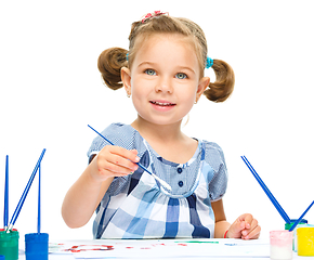 Image showing Little girl is painting with gouache