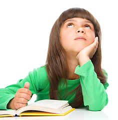 Image showing Young girl is daydreaming while reading book