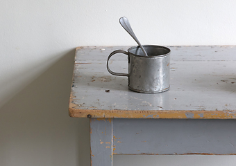 Image showing Very old metal cups and plates on a wooden table