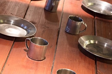 Image showing Very old metal cups and plates on a wooden table