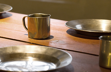 Image showing Very old metal cups and plates on a wooden table