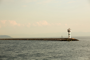 Image showing Beautiful seascape with lighthouse. Calm sea and a lighthouse on the pier. Small beacon in the endless sea. Landscape and beacon. Lighthouse