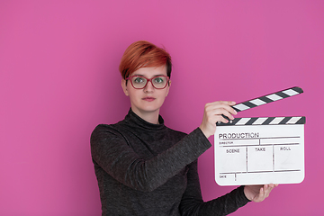 Image showing redhead woman holding movie  clapper on pink background