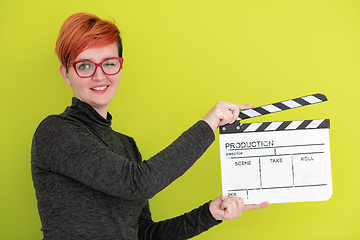 Image showing redhead woman holding movie  clapper on green background