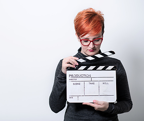 Image showing redhead woman holding movie  clapper on white background