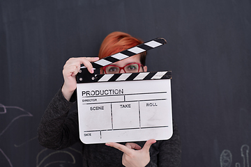 Image showing redhead woman holding clapper on black background