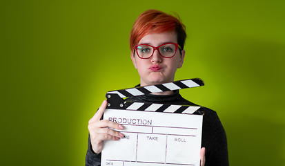 Image showing redhead woman holding movie  clapper on green background