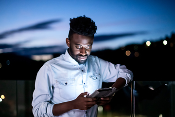 Image showing Young  Afro man on street at night using tablet computer