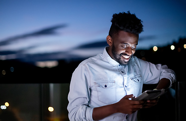 Image showing Young  Afro man on street at night using tablet computer