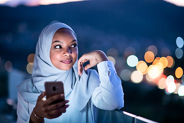 Image showing Young Muslim woman on  street at night using phone