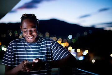 Image showing Young  Afro man on  street at night using phone