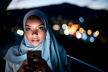 Image showing Young Muslim woman on  street at night using phone