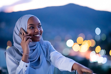 Image showing Young Muslim woman on  street at night using phone