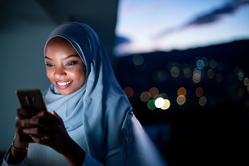 Image showing Young Muslim woman on  street at night using phone