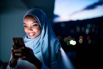 Image showing Young Muslim woman on  street at night using phone