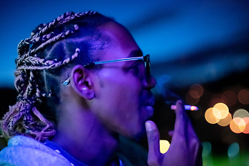 Image showing african american man smoking cigarette  at night