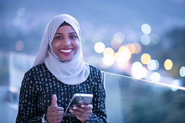 Image showing Young Muslim woman on  street at night using phone