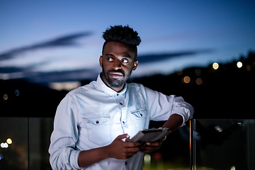 Image showing Young  Afro man on street at night using tablet computer