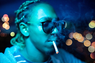 Image showing african american man smoking cigarette  at night